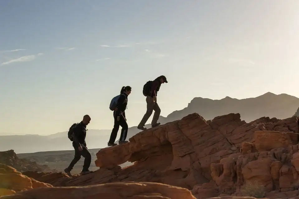 três aventureiros escalando um pico acidentado