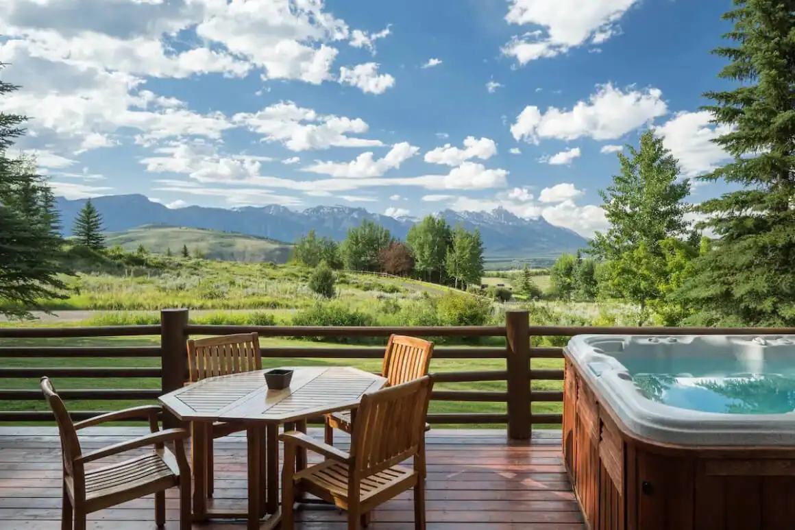 Deck do Mountain Top Lodge com mesa e hot tab com vista para a incrível vista verde da montanha