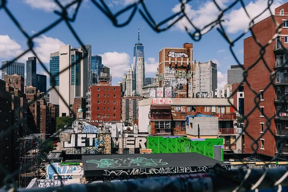 Olhando através da cerca quebrada na Ponte de Manhattan de edifícios cobertos de graffiti em Lower Manhattan