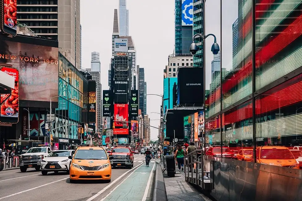 Um táxi amarelo e uma bandeira dos EUA com a Times Square atrás