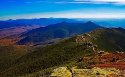Uma garota caminhando em uma montanha com uma mochila e bastões de trekking nas mãos