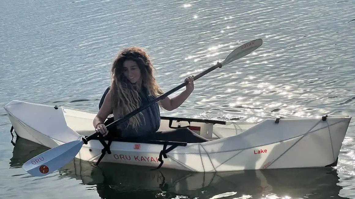 uma garota andando de caiaque sozinha em um lago de águas calmas