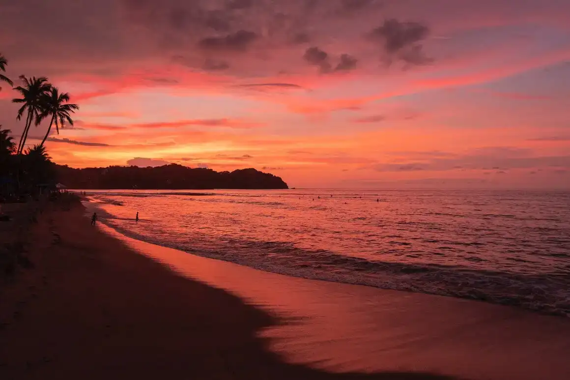 La noia somriu alegrement mentre es troba en un penya-segat amb vistes a una platja de Zipolite, Mèxic.