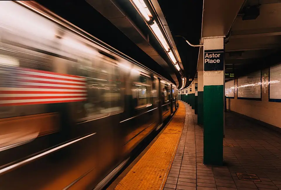 Sebuah kereta api bawah tanah di NYC memandu laju melalui stesen metro Astor place. New York, Amerika Syarikat. Fotografi kelajuan pengatup panjang.