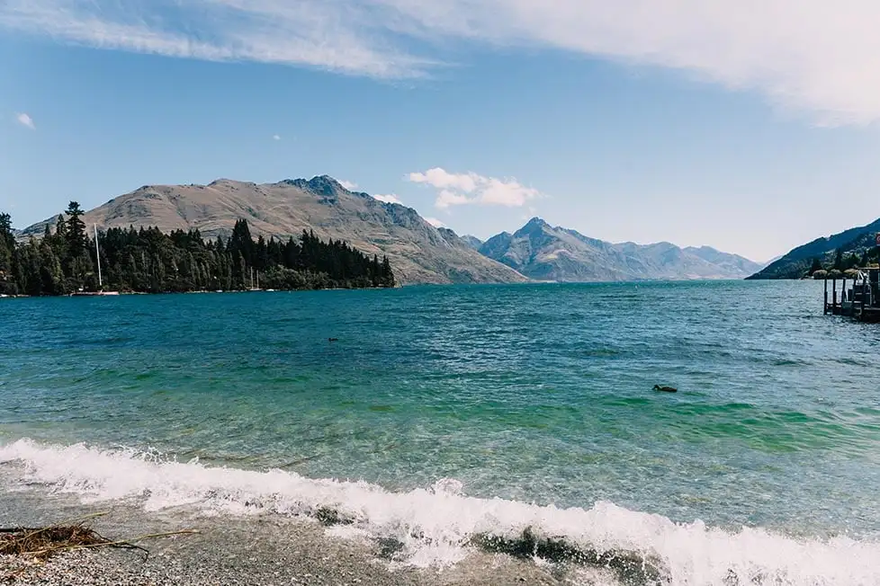 As águas verde-azuladas do lago e a cordilheira Remarkables, em Queenstown, Nova Zelândia
