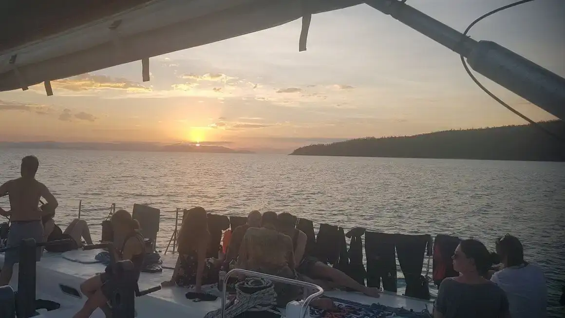 Lidé relaxují při sledování západu slunce na výletě lodí na ostrovech Whitsunday
