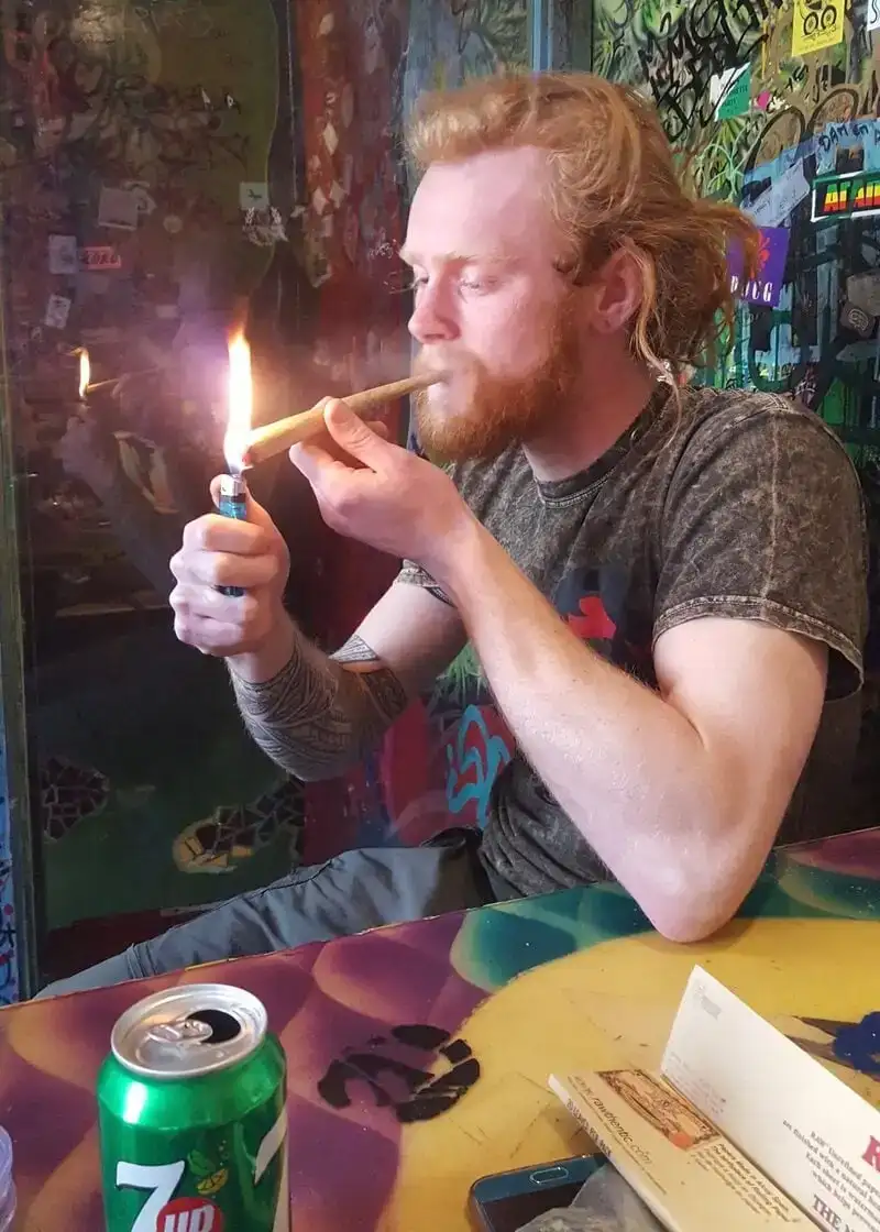 Ginger man allumant un joint surdimensionné dans un coffeeshop à Amsterdam