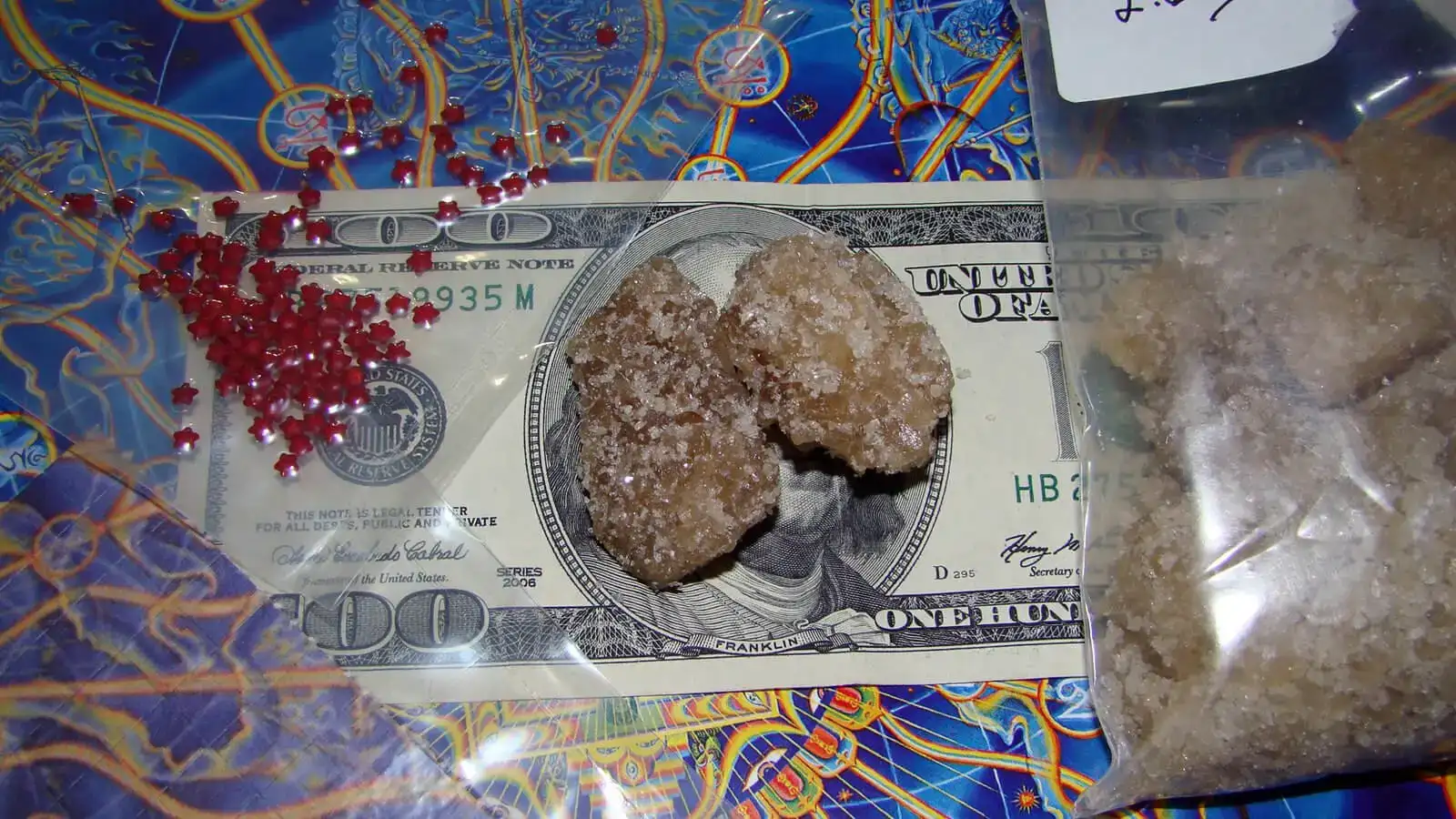 Drogues achetées sur la route : cristaux de MDMA et quelques micropoints de LSD posés sur un billet de 100 USD