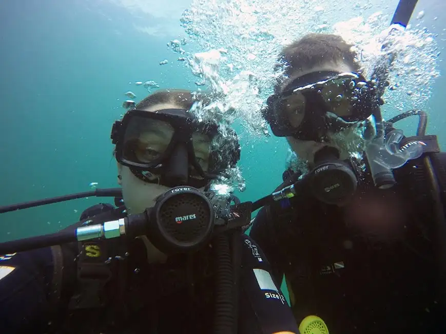 Deux personnes prenant un selfie en plongée sous-marine.