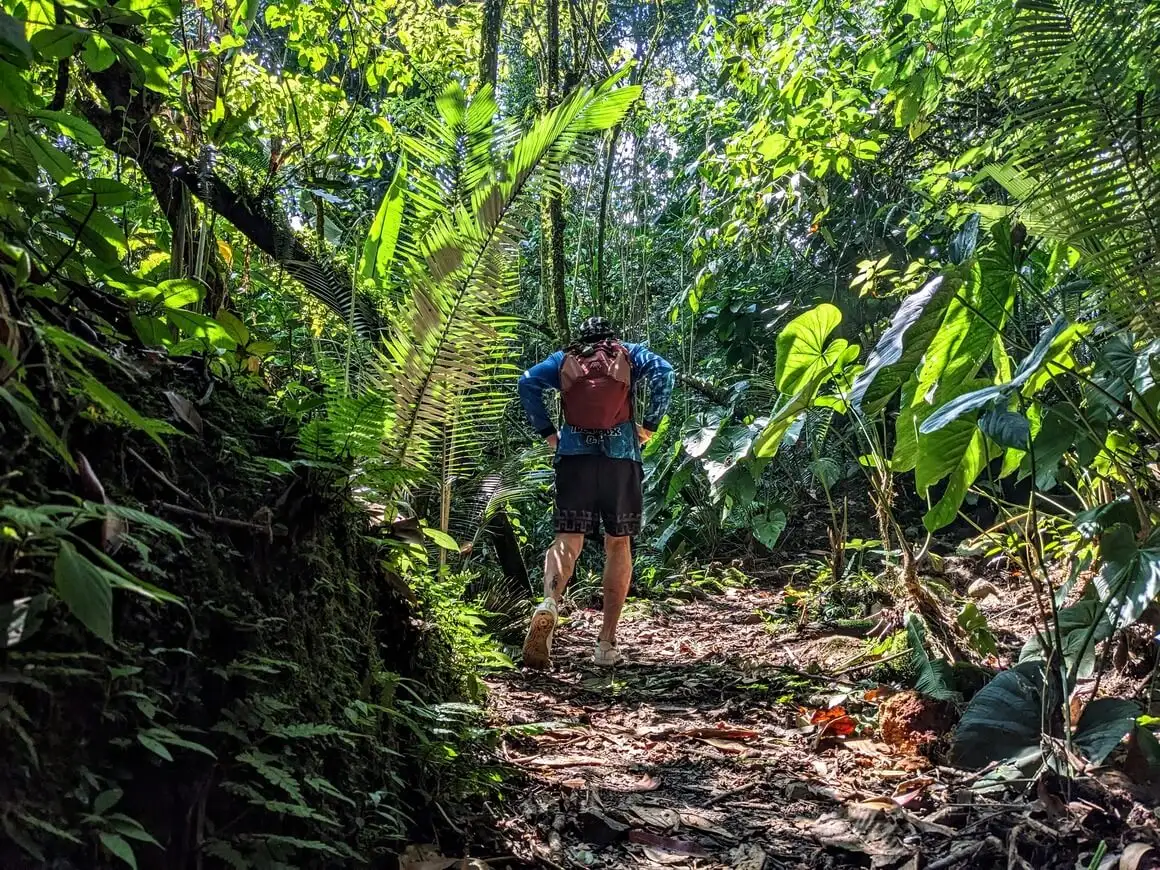 Seba usando uma mochila Osprey andando pela selva colombiana