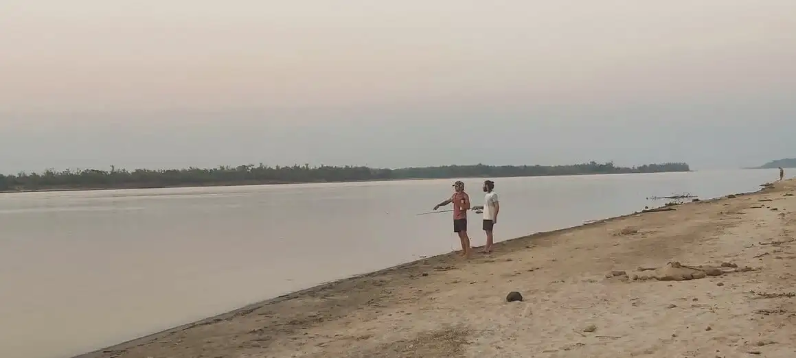 deux personnes se tenaient sur les rives sablonneuses d'une rivière