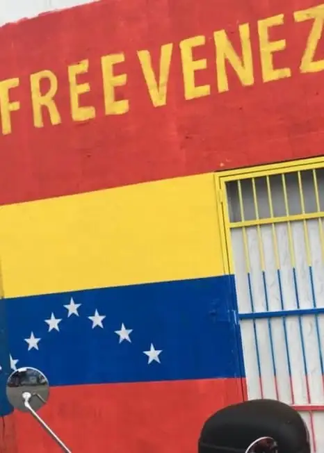 Drapeau vénézuélien peint sur un mur et des barres avec VENEZUELA GRATUIT écrit ci-dessus