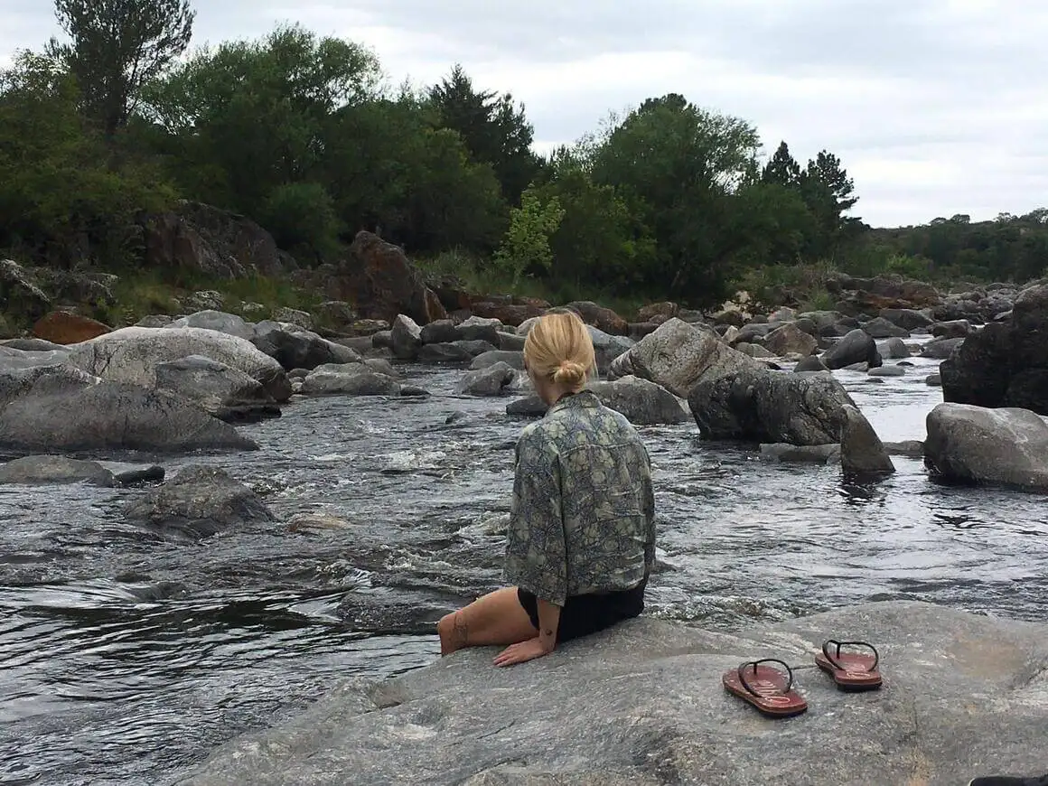 Femme assise au bord d’une rivière en Amérique du Sud, sans ses tongs