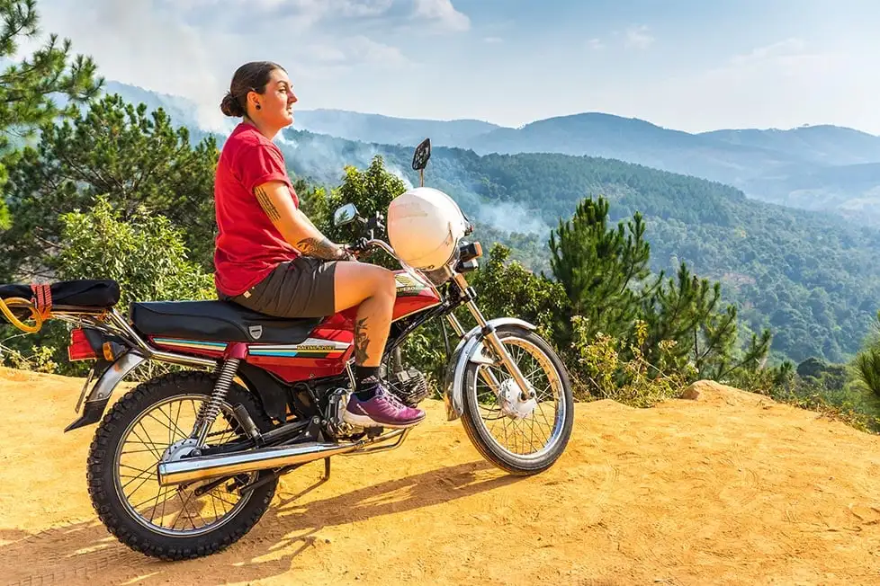 Une personne assise sur une moto regardant les montagnes couvertes de jungle du Vietnam.