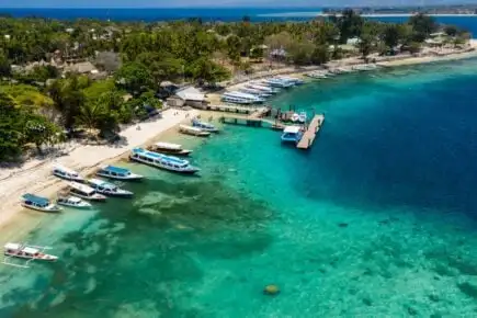 un gruppo di viaggiatori si riunisce con alcuni drink mentre suona musica vicino al porto di Gili Air, in Indonesia