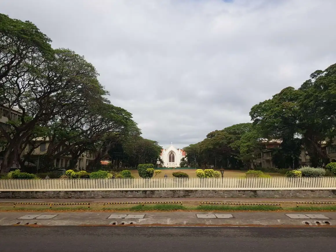 Parc universitaire Silliman à Dumaguete avec des arbres luxuriants et leurs ombres sous un ciel captivant