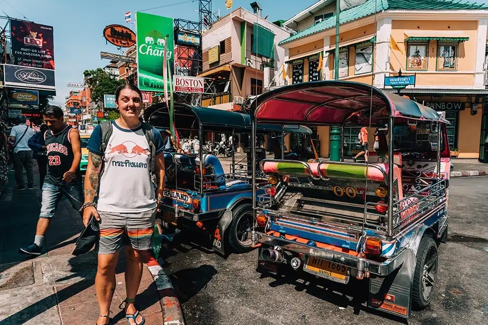 Osoba koja stoji na Khao San Roadu u Bangkoku, Tajland pored nekih klasičnih tajlandskih tuk tuka svih boja.