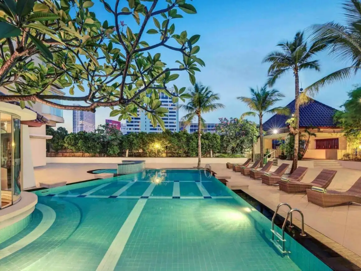 Stromy frangipani nad bazénom s osvetleným dnom v hoteli Mercure Jakarta Kota