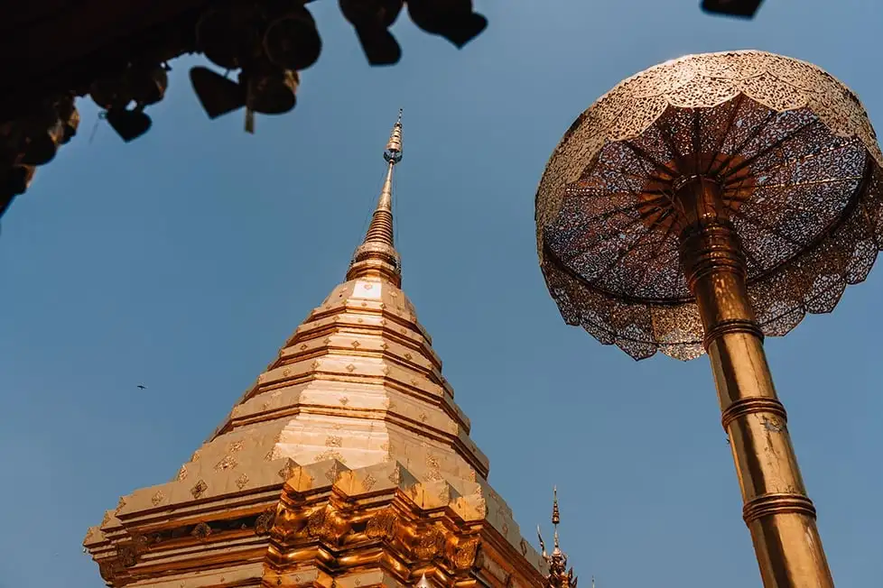 Uma pessoa parada em uma montanha em Doi Chiang Dao, carregando uma mochila vermelha e estendendo os braços