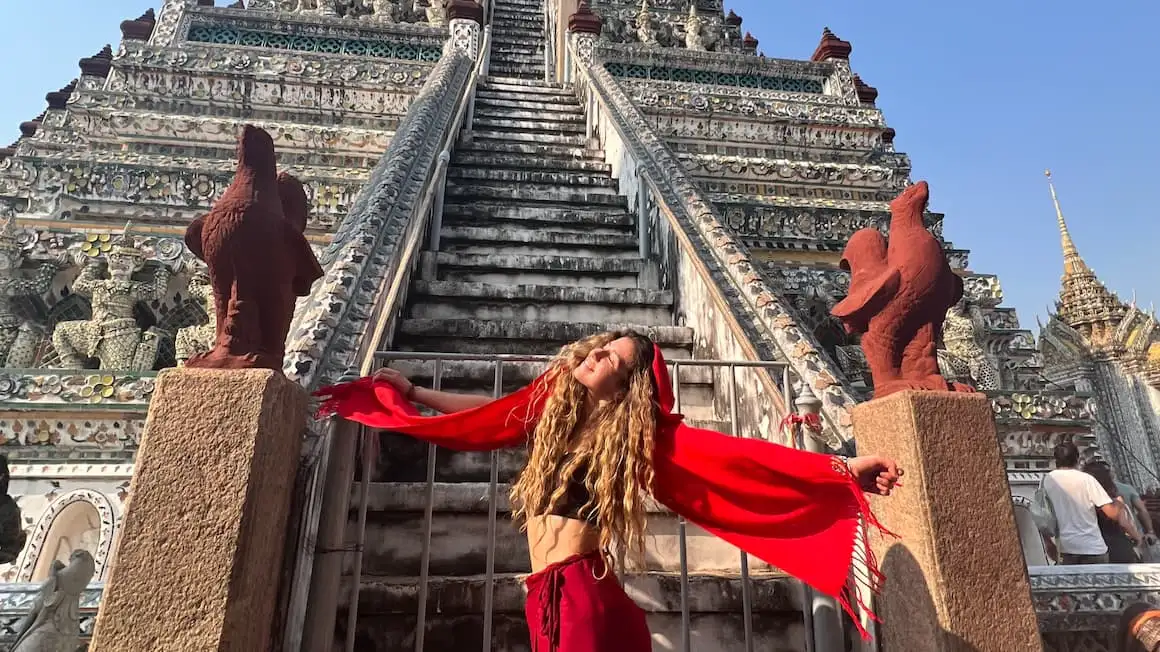 une fille devant Wat Arun, temple en Thaïlande, se sentant heureuse