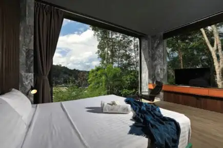 Une chaloupe traditionnelle thaïlandaise flotte dans les eaux turquoise au bord d'une falaise calcaire près de Phuket.