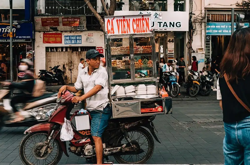 Vietnam'daki bir caddede sokak yemeği satan motosikletli bir adam