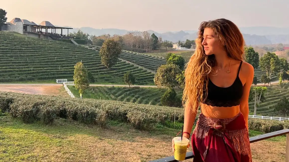 une fille souriante avec un thé vert glacé à la main, regardant le coucher du soleil