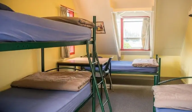 Lits superposés simples en métal dans une chambre jaune ensoleillée de l'auberge Southern Laughter Backpackers à Queenstown, Nouvelle-Zélande