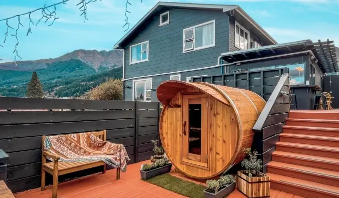 Sauna sphérique sur une terrasse avec une grande maison en arrière-plan à l'auberge Black Sheep Backpackers à Queenstown, Nouvelle-Zélande