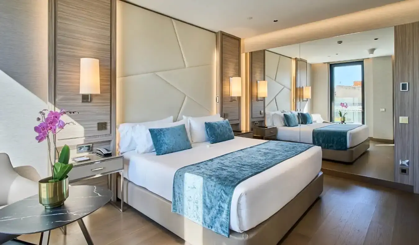 Un lit king size dans une chambre d'hôtel au design contemporain, un grand miroir et des orchidées sur la table du VP Plaza España Design à Madrid, Espagne