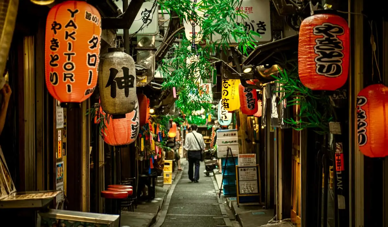 Um viajante explorando um beco estreito e escuro na área de Shinjuku, em Tóquio, Japão