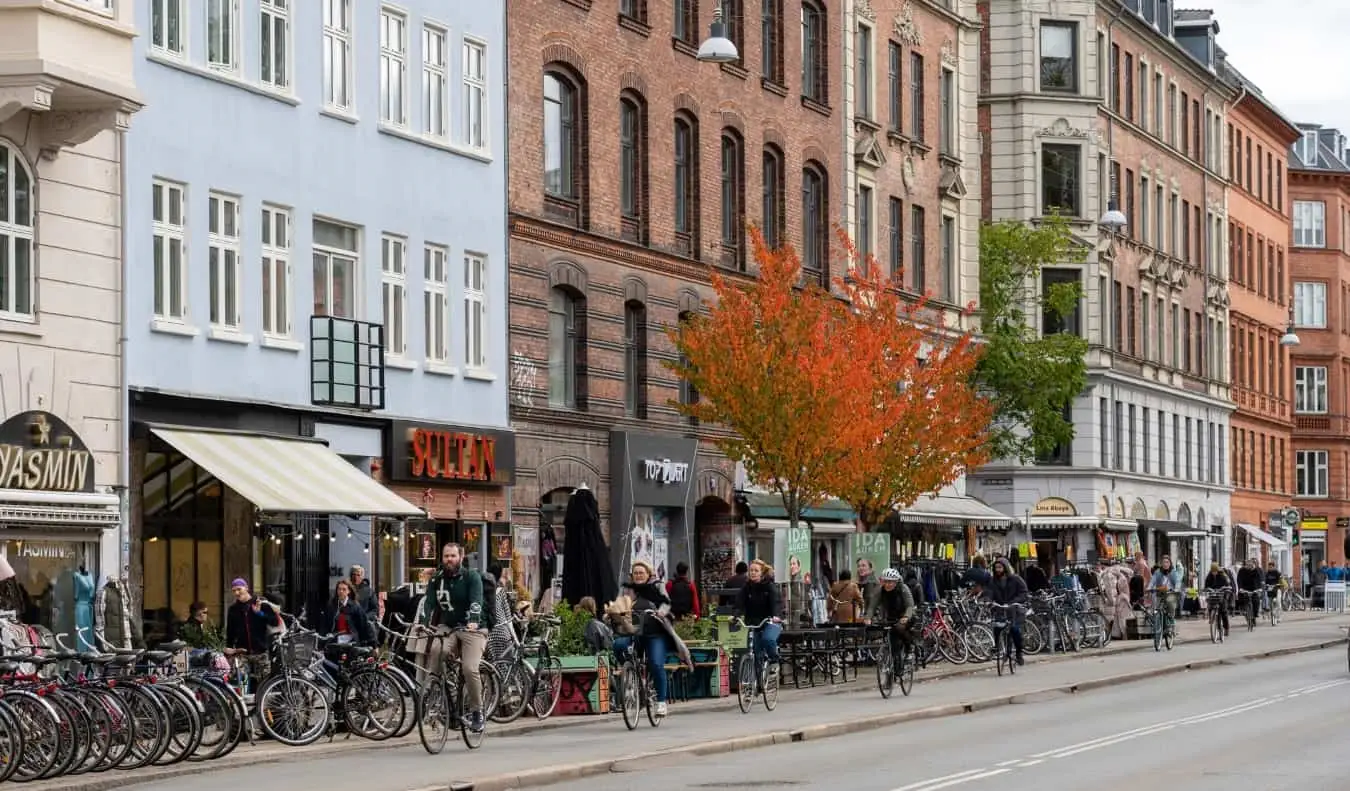 Les gens font du vélo dans une rue bordée de restaurants dans le quartier de Nørrebro à Copenhague, au Danemark