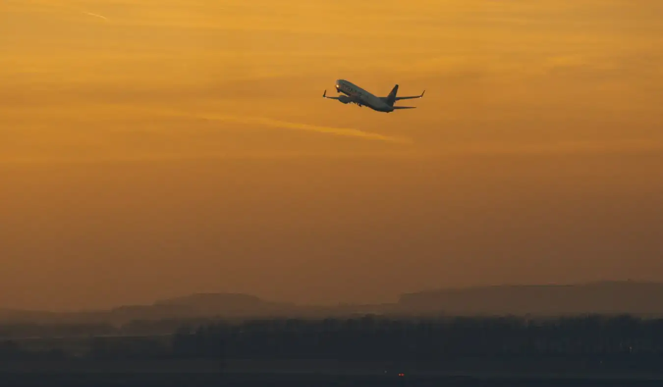 Um avião decolando durante um pôr do sol laranja brilhante