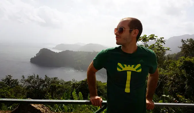 Scott posant devant un paysage vallonné luxuriant près de l'océan