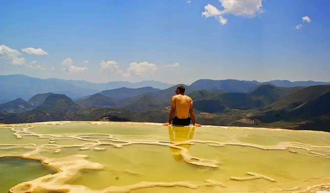 Scott assis devant des salines entourées de forêts et de collines luxuriantes