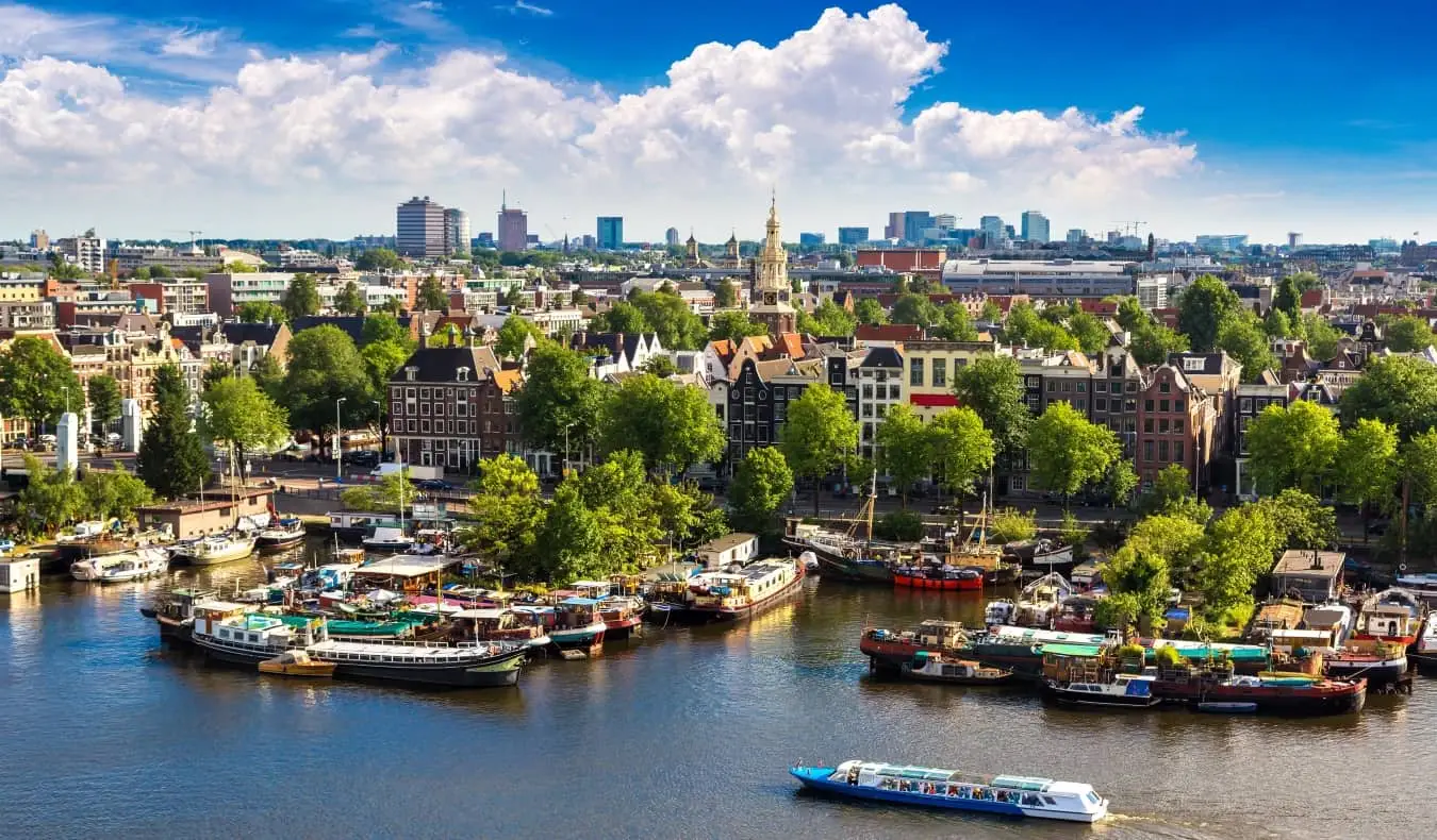 Vista panorâmica do horizonte de Amsterdã com barcos atracados e flutuando ao longo de um rio em primeiro plano