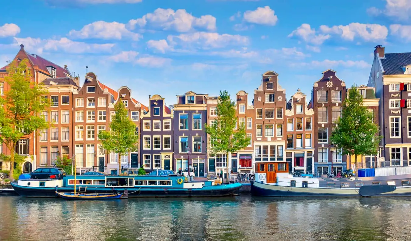Um dia ensolarado ao longo das fileiras de casas antigas perto do canal em Amsterdã