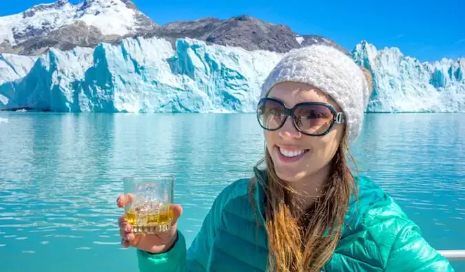 Samostatná cestovatelka Kristin Addis pózující s drinkem poblíž ledovce O’Higgins v Patagonii