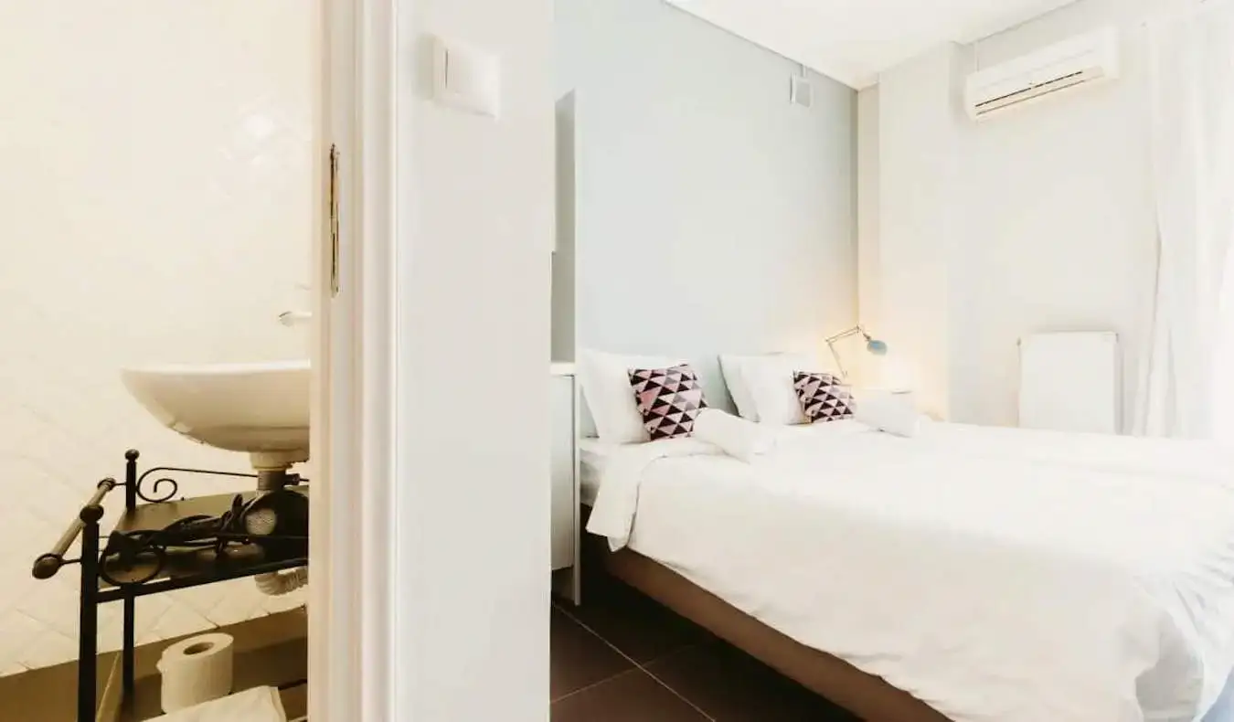 Um espaçoso quarto privado no Athens Studios, na Grécia, com uma cama grande e branca