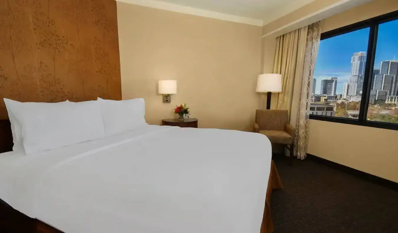 Jednoduchý pokoj pro hosty s manželskou postelí v Embassy Suites by Hilton v Austinu v Texasu