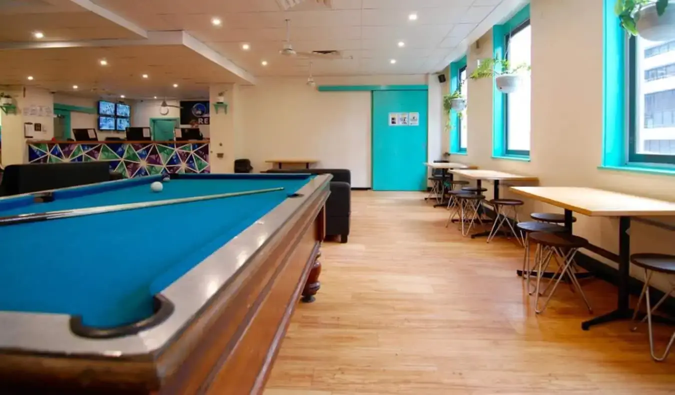 Espace commun avec tables et table de billard à l'auberge Flinders Backpackers à Melbourne, en Australie.