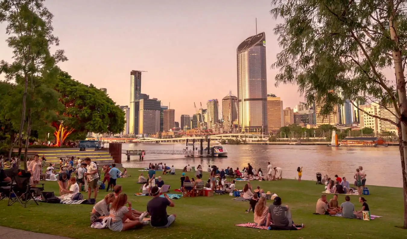 Pessoas relaxando à beira de South Bank, perto da água, olhando para o CBD de Brisbane, Austrália