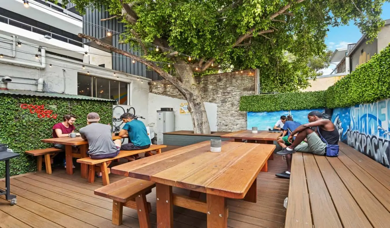 pátio externo com mesas e bancos de piquenique de madeira no Summer House Backpackers Hostel em Sydney