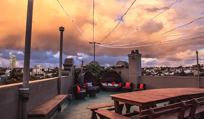 Terraço na cobertura com mesas de piquenique ao pôr do sol no Kings Cross Backpackers em Sydney, Austrália