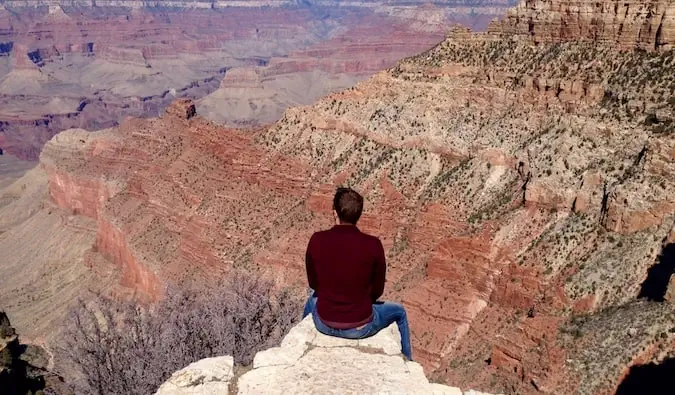 Mark Manson sedící na okraji Grand Canyonu v USA