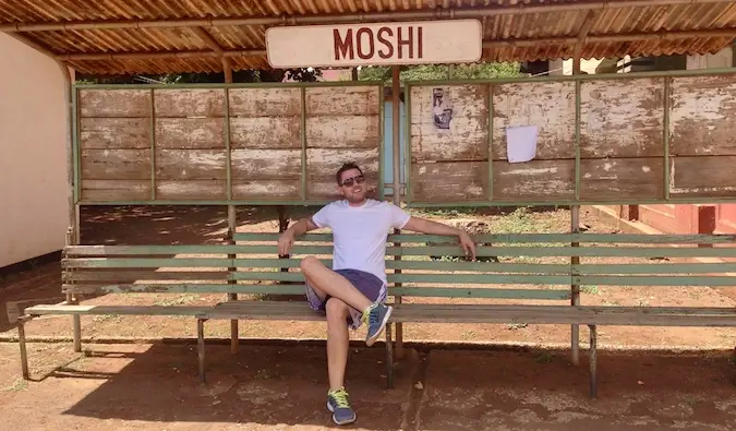 Mark Manson sedí na autobusové zastávce v Moshi, Tanzanie