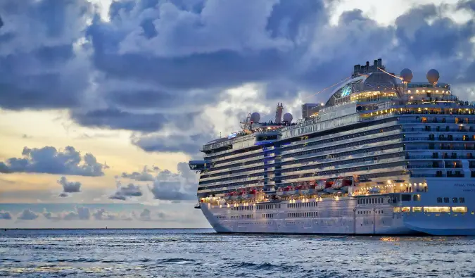 Un grand bateau de croisière naviguant vers un coucher de soleil nuageux