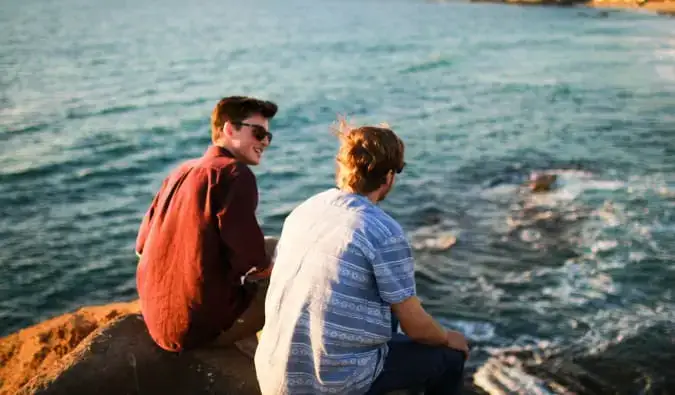 Deux voyageurs masculins assis au bord de l'eau et se parlant