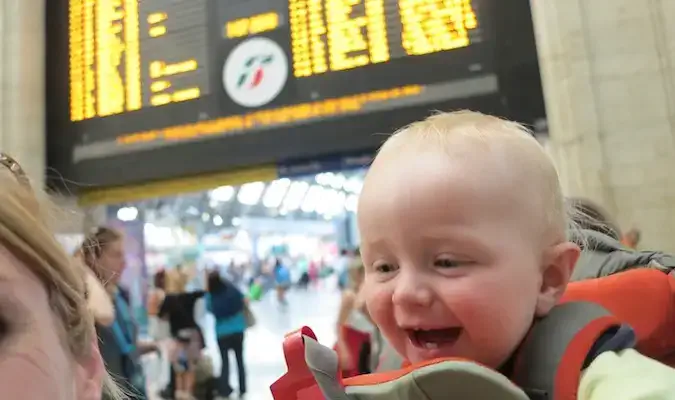 filho em um carrinho de bebê posando em uma estação de trem na Europa