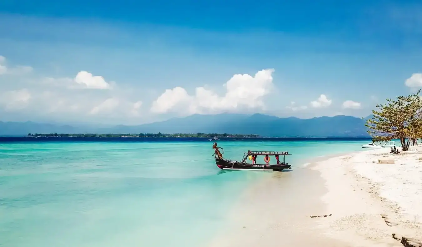 uma linda praia com um barco estacionado ao longo da costa nas Ilhas Gili, Indonésia